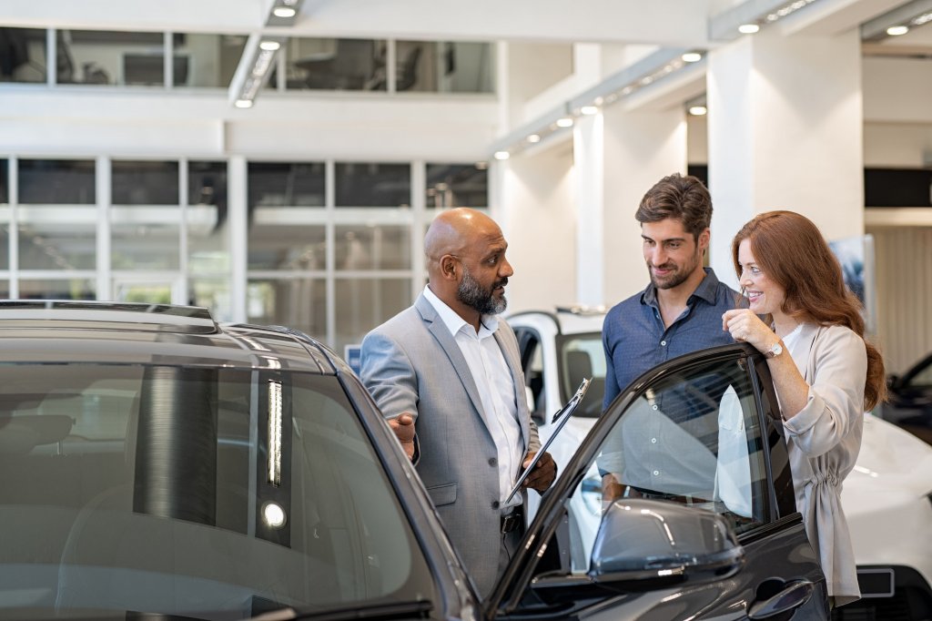 Car Salesman showing a couple the exterior of a vehicle