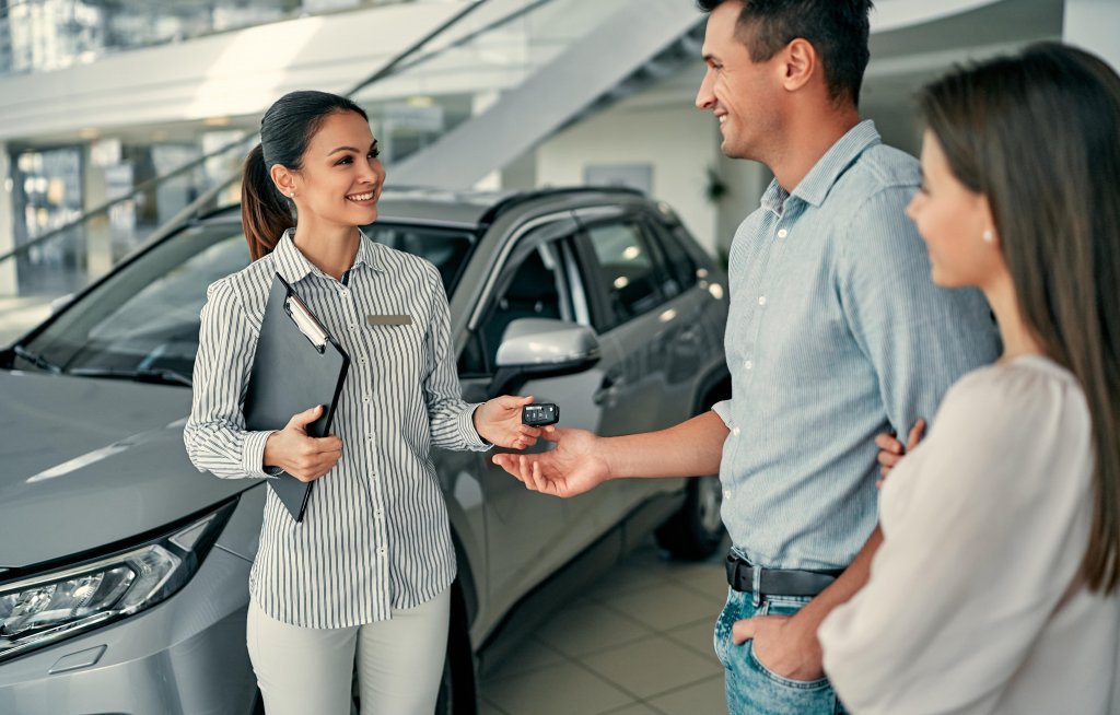 Car Saleswoman talking to customers handing them keys