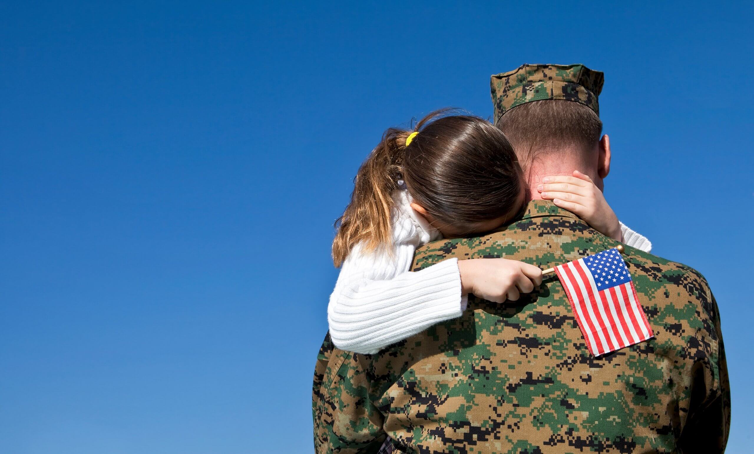Little girl hugging her dad who is a veteran in uniform