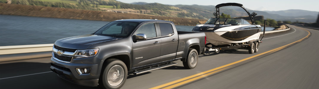 Grey 2015 Chevy Colorado towing a boat on the road