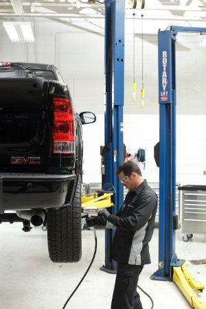 man rotates tires on a GMC vehicle