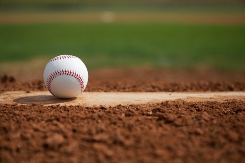 lone baseball on a mound in the late afternoon sun