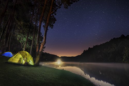 tent on the side of a lake in the dark of night