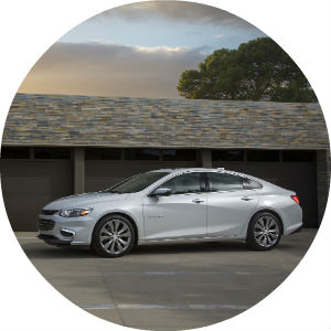 a white Chevy sedan against the background of a darker garage door