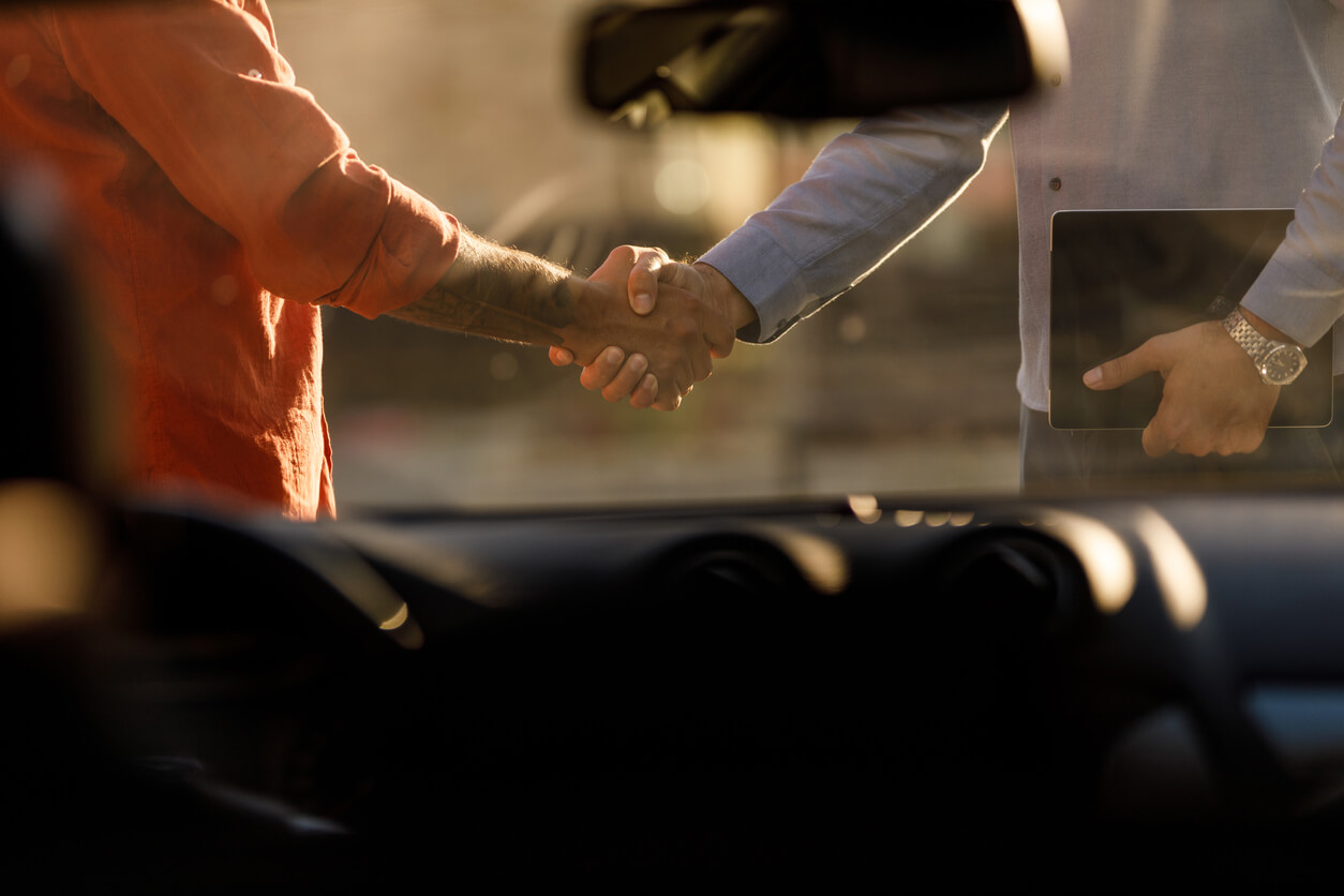 Selective focus shot of unrecognizable man and car salesman shaking hands after successful collaboration.