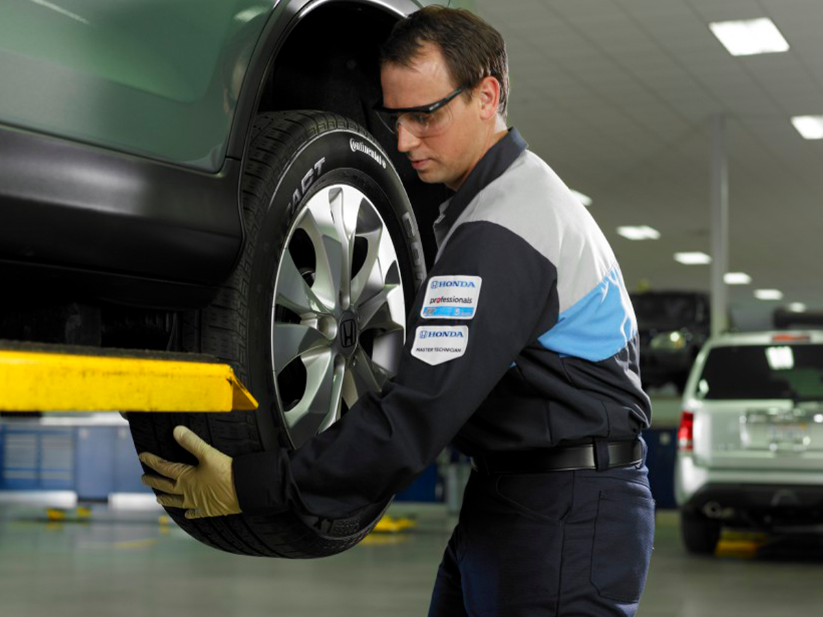A honda service technician places a tire on a Honda. Get your service at Midlands Honda in Columbia, SC.