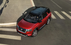 A red Nissan Pathfinder turns on a city corner.