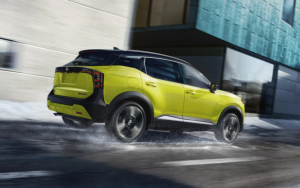 A 2025 Nissan Kicks in Yuzu Yellow Metallic and Super Black drives on the highway. 