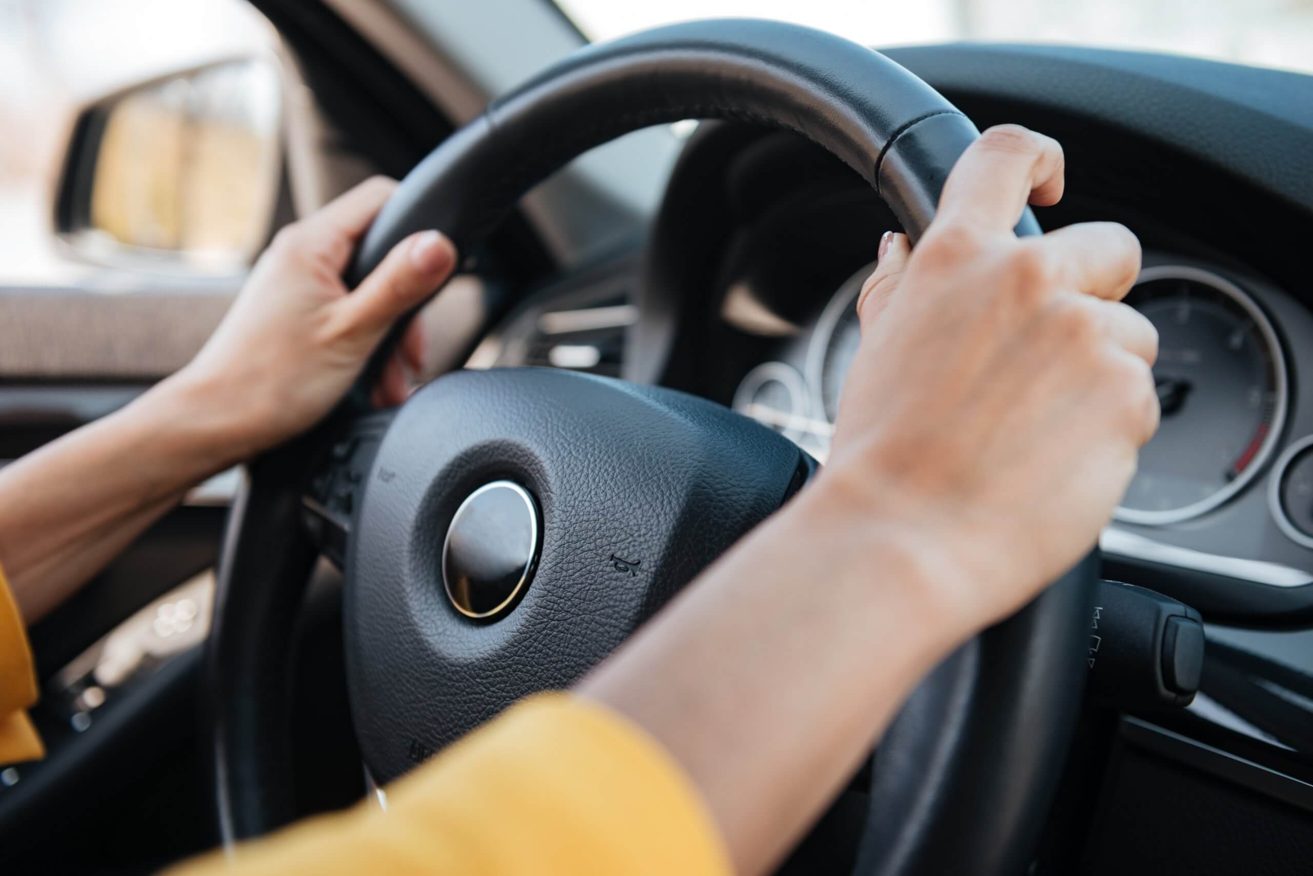 Person with hands on the steering wheel of a car