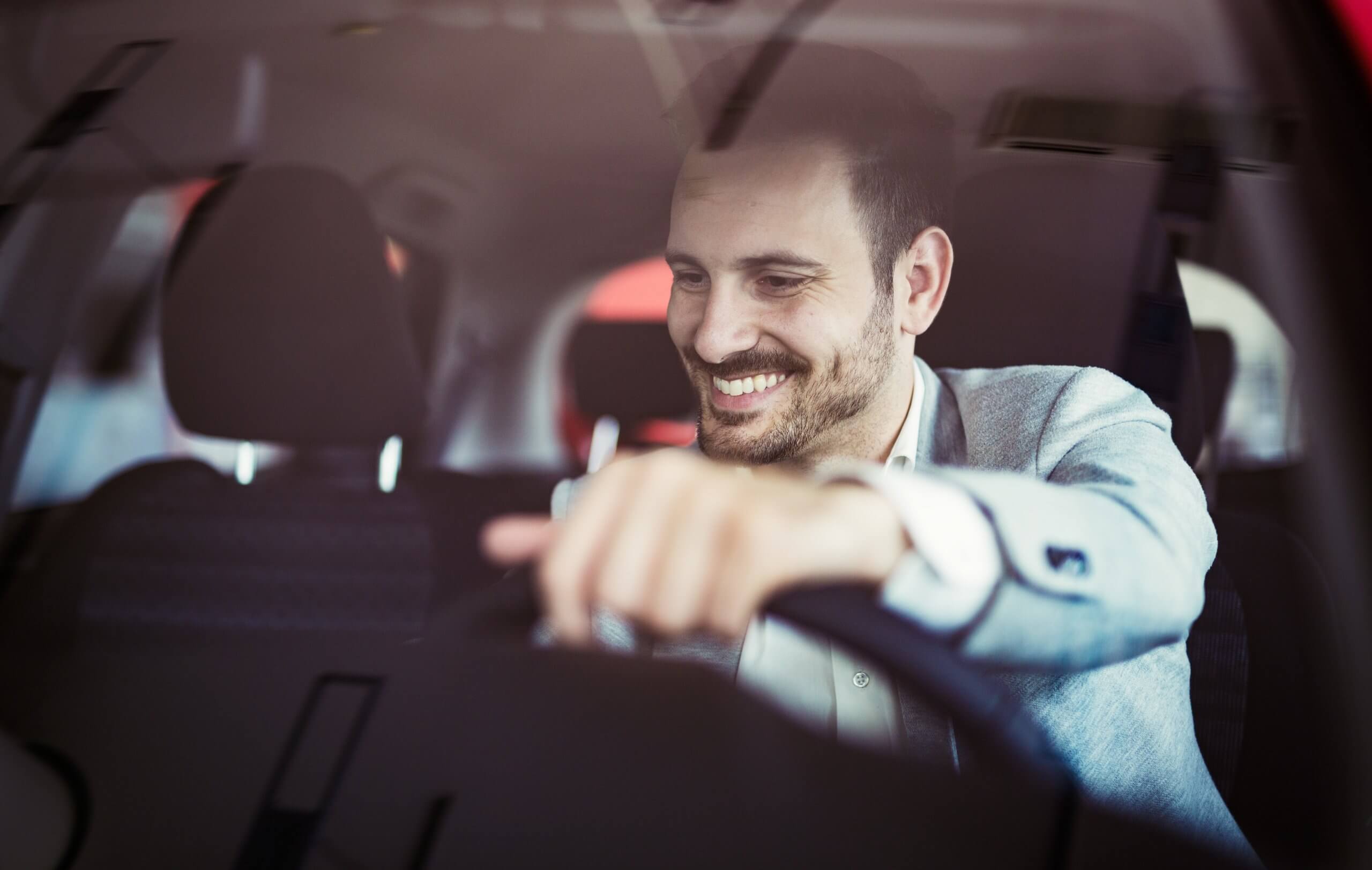 Man smiling in his car with hand on the steering wheel