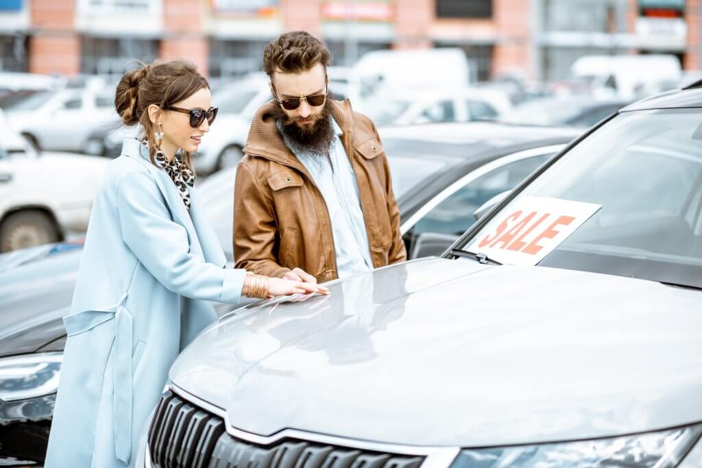 Man and woman choosing car to buy outdoors