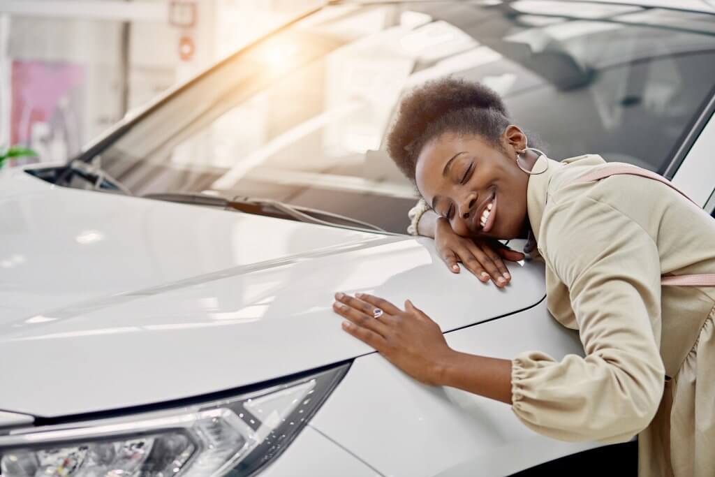 smiling black lady hugs her new auto