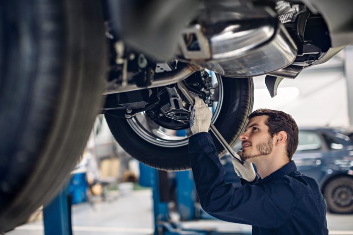 Auto car repair service center. Mechanic examining car suspension