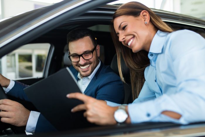 Saleswoman at the dealership showroom talking with customer and