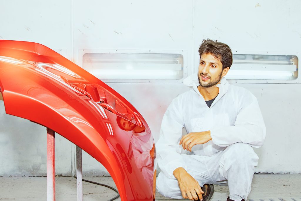 auto technician reviewing a fiberglass bumper after repairs
