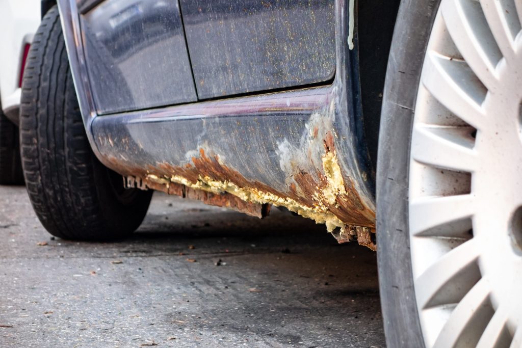 Rusted undercarriage of a car with wheels in view