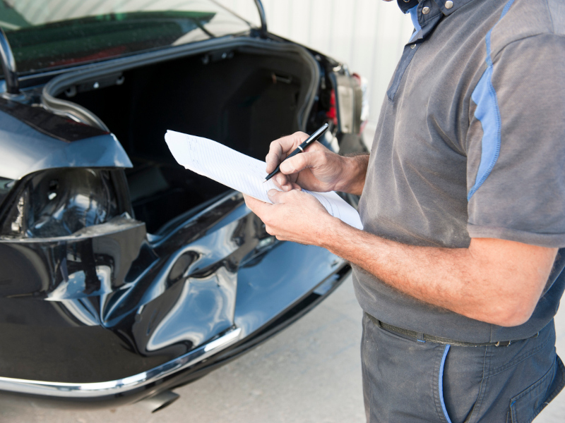 Man examining car rear end body damage