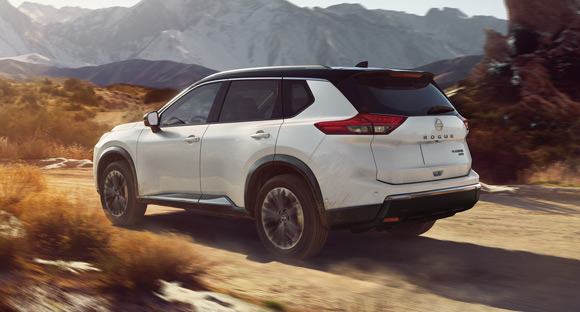 Red SUV driving on mountain highway with scenic landscape