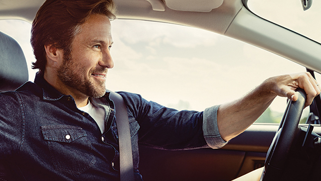 Interior view of a man driving a Cadillac vehicle.