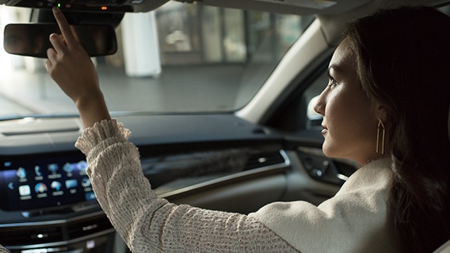 A passenger presses the OnStar button inside a Cadillac.