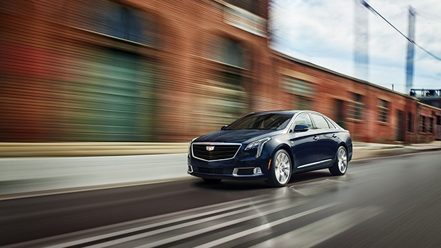 A passenger presses the OnStar button inside a Cadillac.