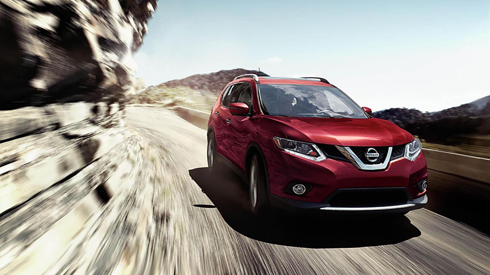 Red Nissan Rouge Driving down a mountainous road