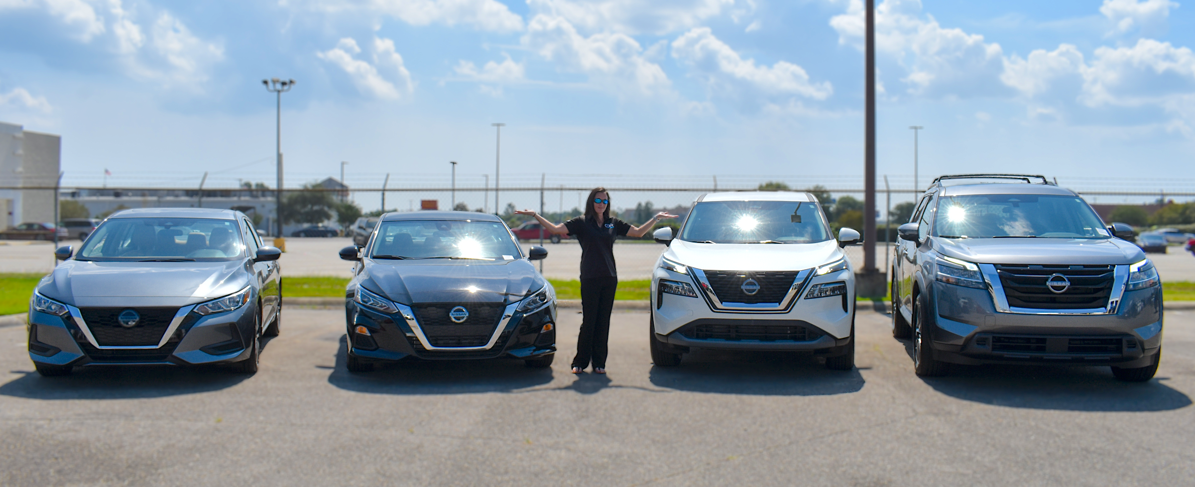 Lineup of Nissan vehicles in red with a highway overpass in the background.