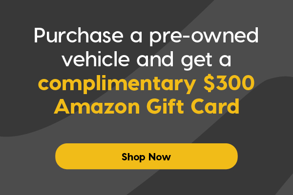 Promotional banner featuring a white Chevrolet Silverado pickup truck and a white GMC Terrain SUV with two Amazon.ca gift cards in the background. Text offers a complimentary $300 Amazon gift card with the purchase of a pre-owned vehicle, alongside a yellow "Shop Now" button. Promo ends August 10, 2025