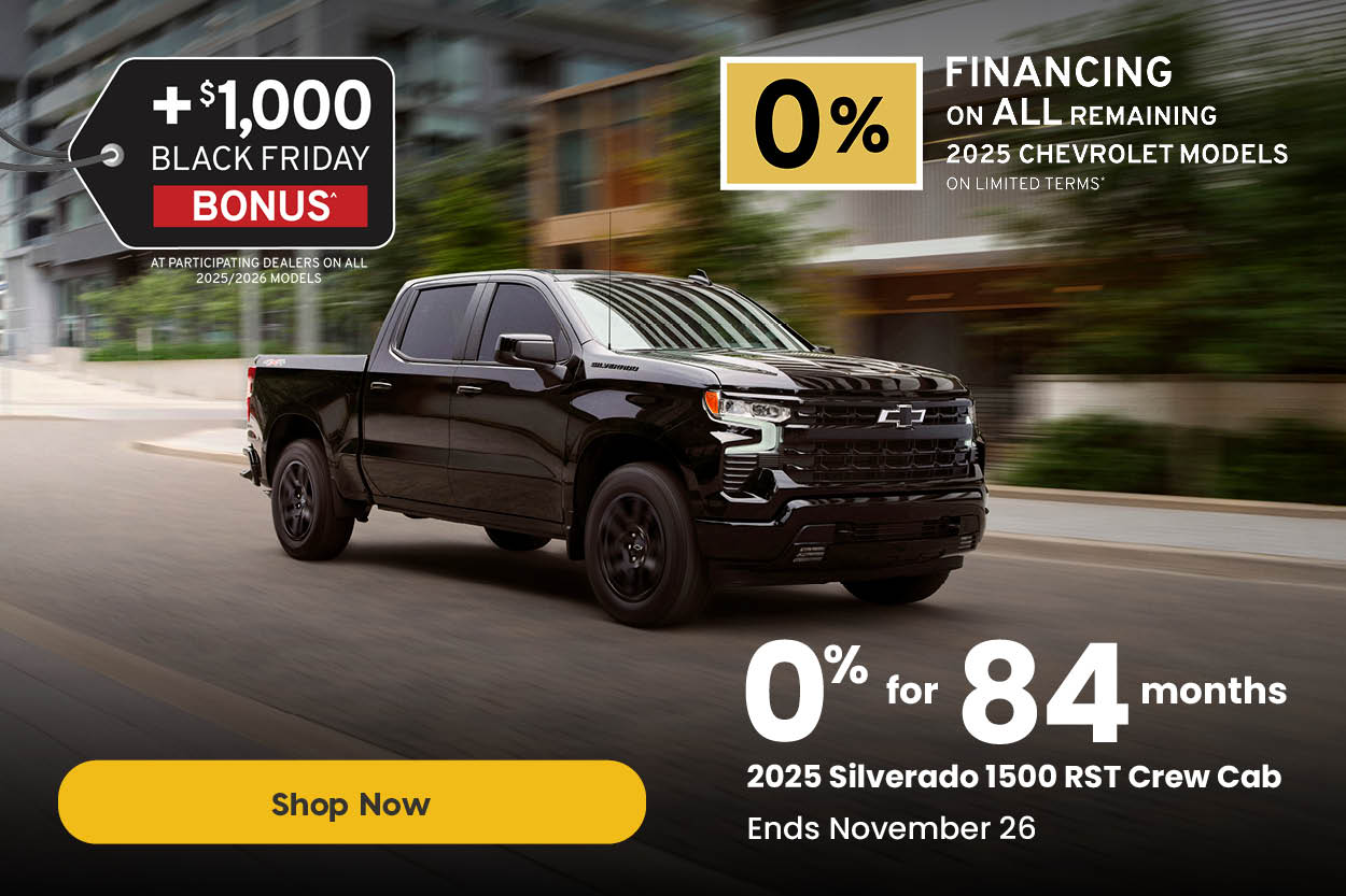 Black 2025 Chevrolet Silverado 1500 RST Crew Cab driving through a city street. Text reads: “+$1,000 Black Friday Bonus at participating dealers on all 2025/2026 models. 0% for 84 months on the 2025 Silverado 1500 RST Crew Cab. Ends November 26.” A yellow button reads “Shop Now.”