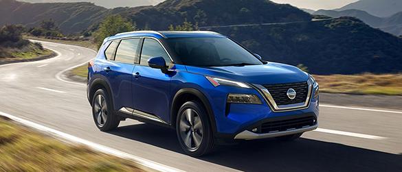 A blue Nissan Rogue driving down a curvy highway.