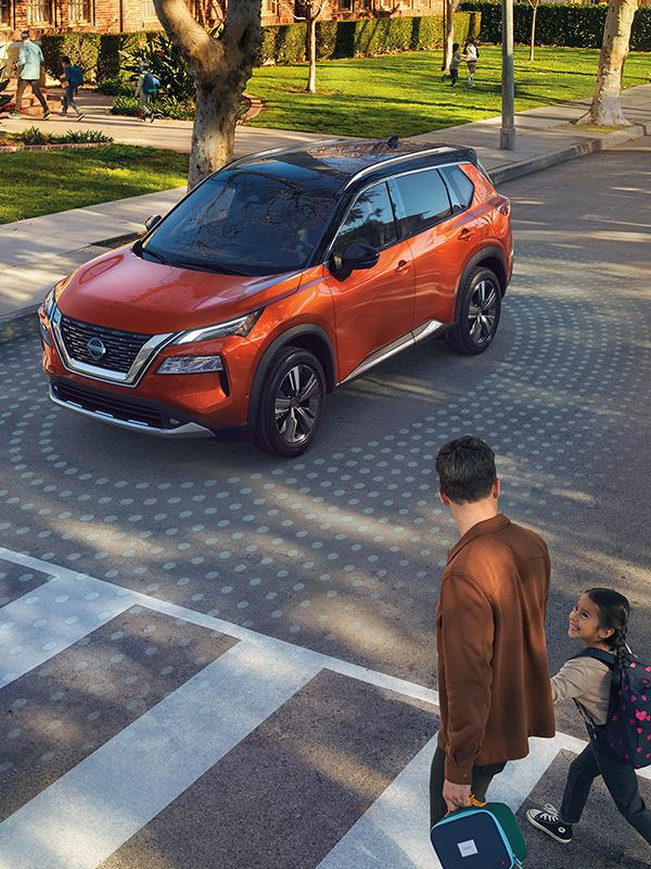 An orange Nissan Rogue at a school drop-off site.