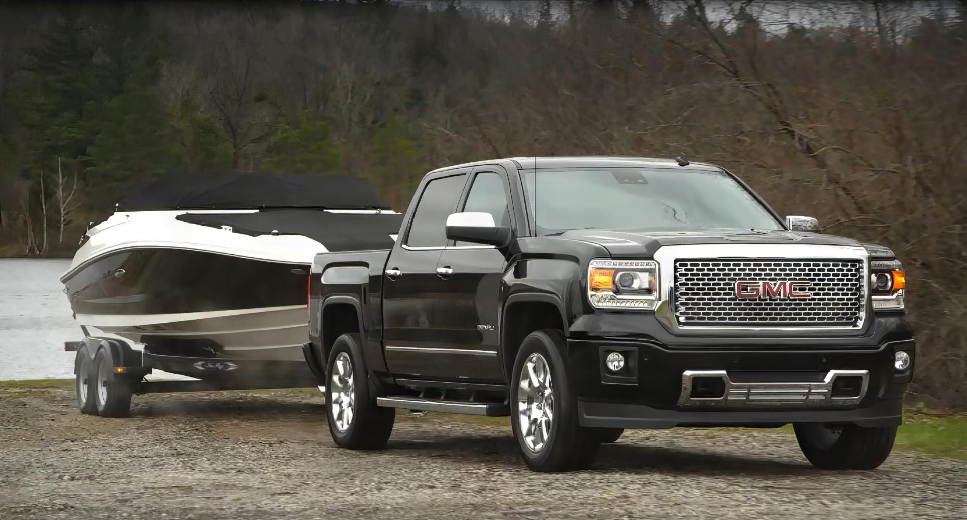 A GMC Sierra 1500 Denali in 3/4 profile towing a boat on a cloudy day