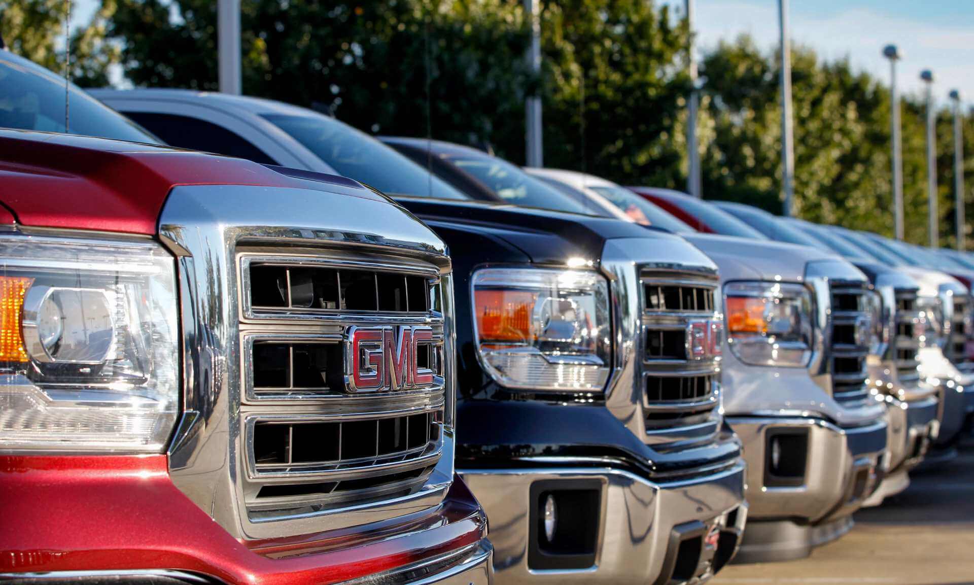 A lot selling older GMC Sierra trucks in various colours