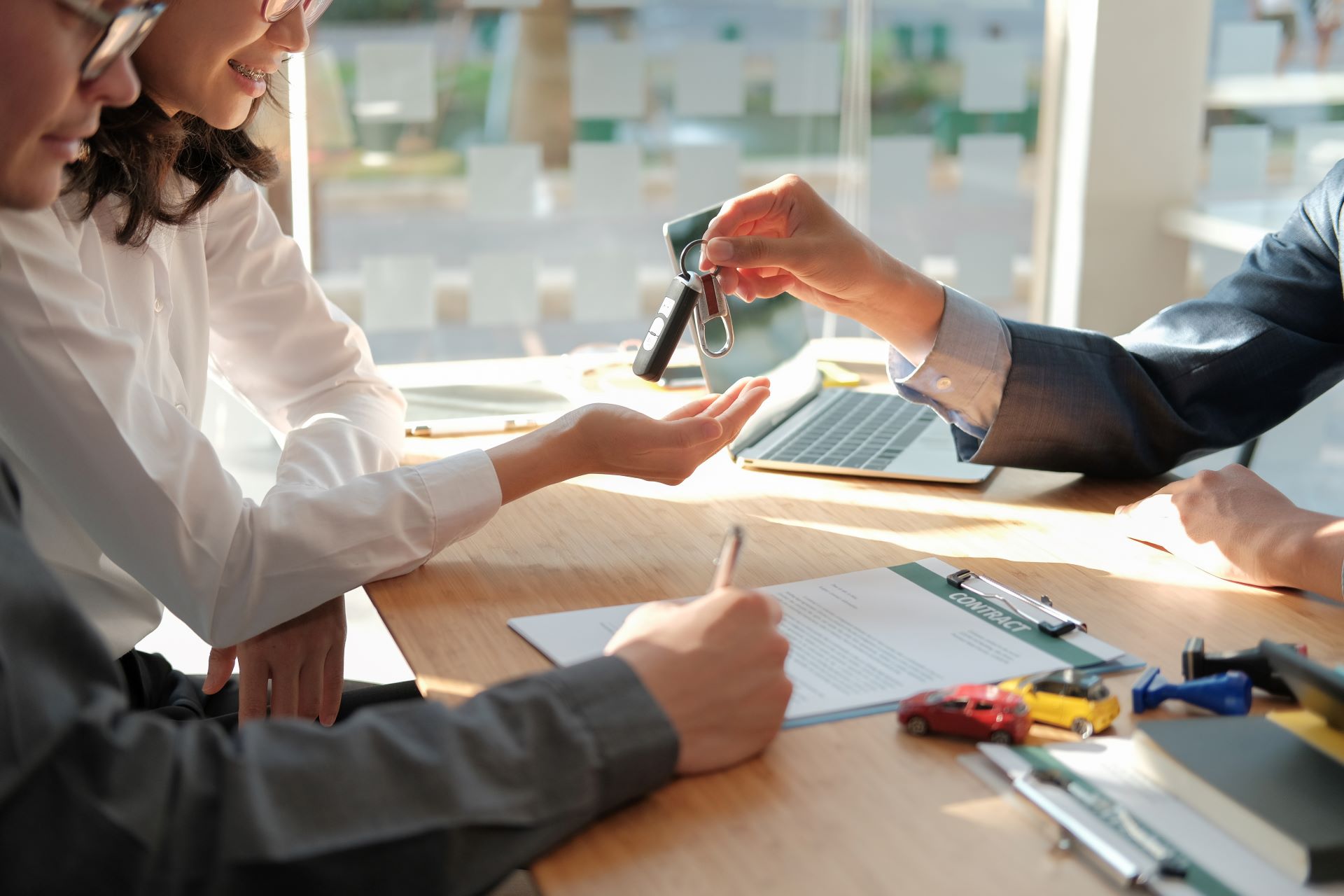 Couple financing car at dealership and receiving car keys