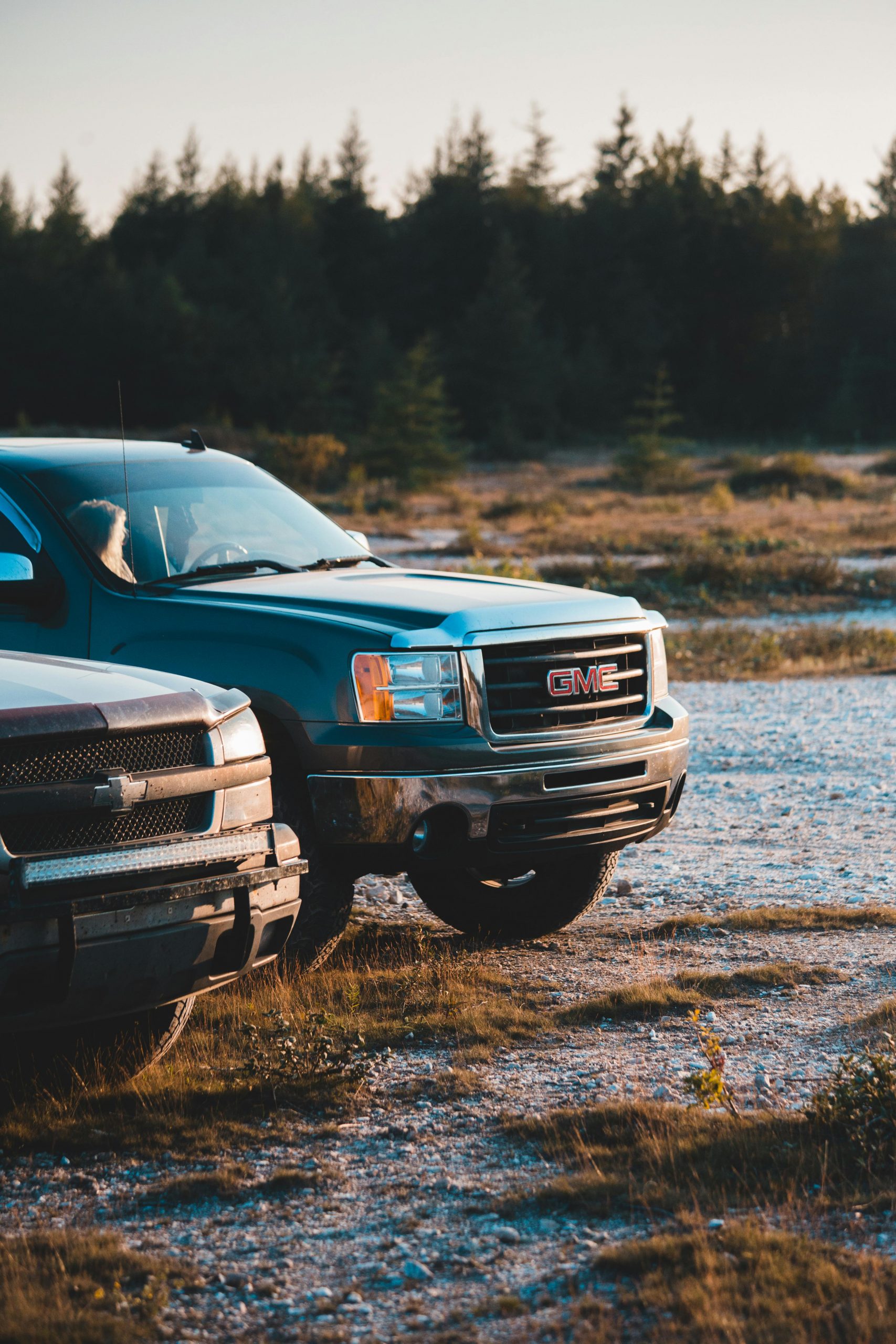 Two pickup trucks parked on a dirt road