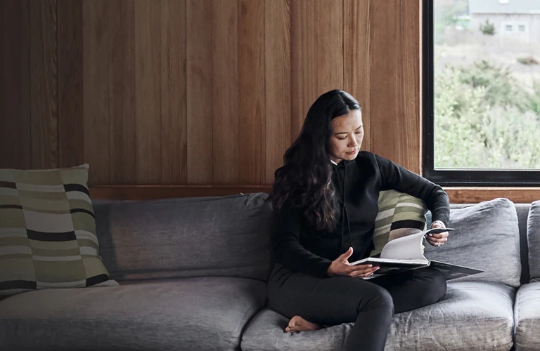 Woman sitting on a couch looking through INFINITI papers