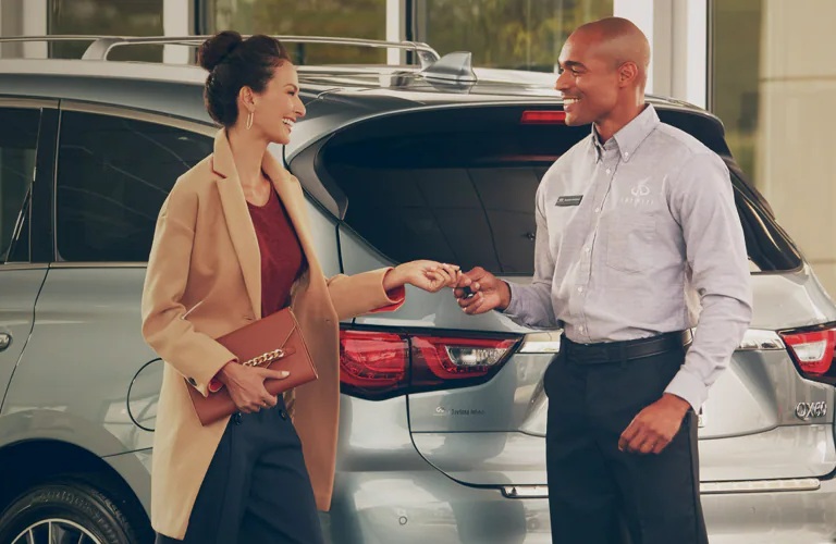 INFINTI salesman giving SUV keys to a woman