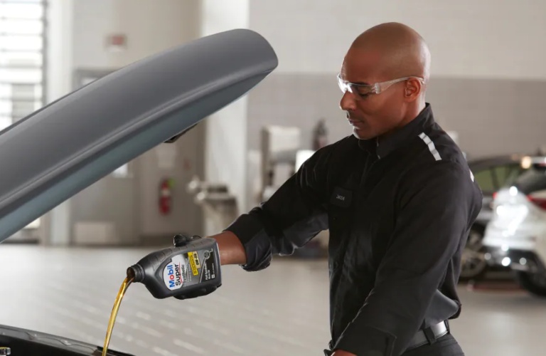 An INFINITI service tech pouring Mobil oil into an INFINITI model