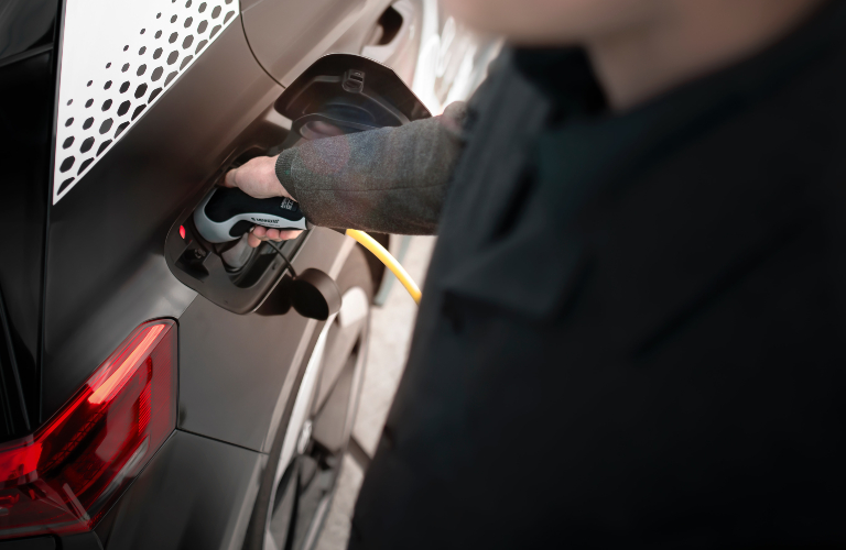 man charging electric vehicle