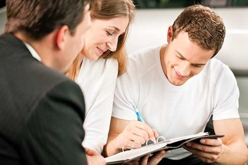 Couple signing purchase papers for car