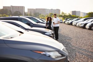 Car-Dealer-Showing-Vehicle-to-a-Customer-in-Outdoor-Lot