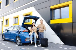 Couple-Waiting-While-Charging-Electric-Vehicle-on-a-Road-Trip