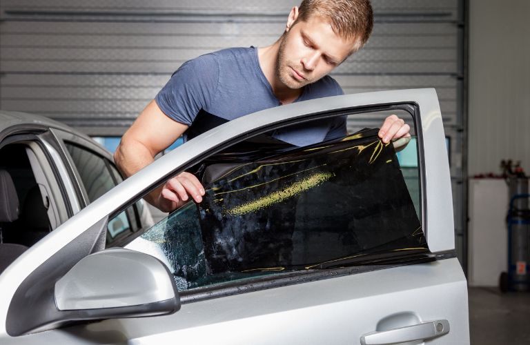 Tinted dark glass foil removal from car window. Stock Photo by