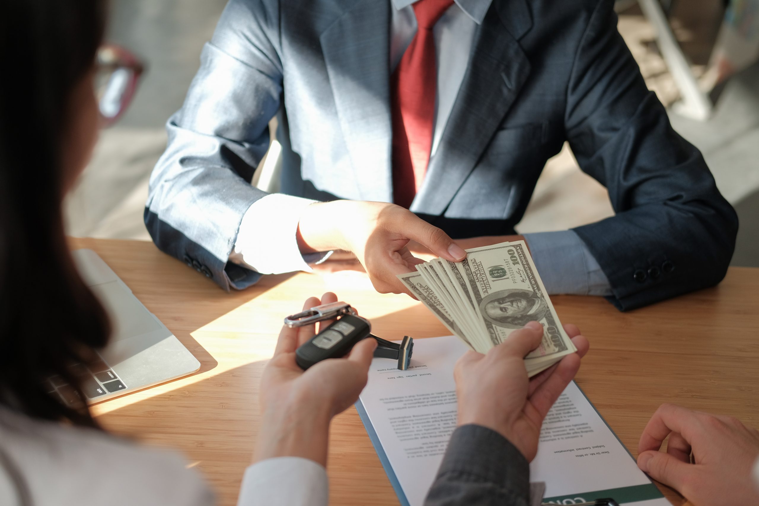 Man receiving money and couple receiving car keys