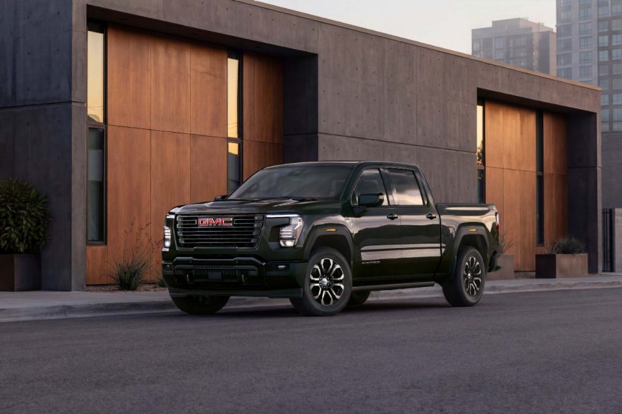 Dark green 2027 GMC Sierra 1500 parked in front of a modern desert home at dusk