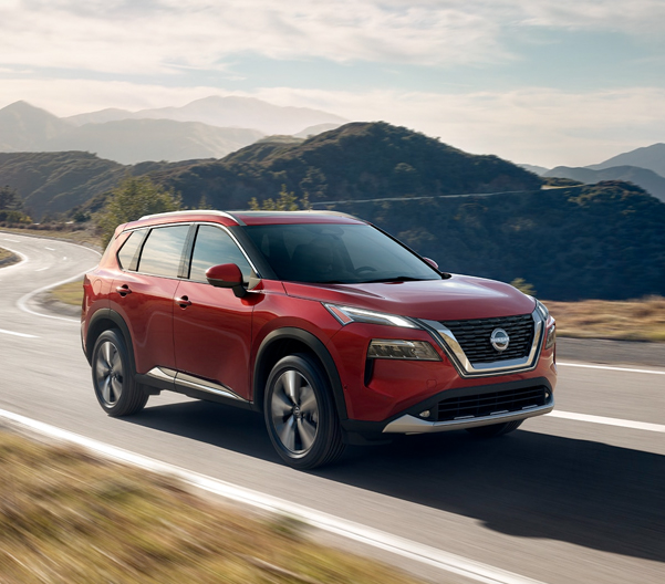 2023 Nissan Rogue in Scarlet Ember Tincoat on a mountain road.