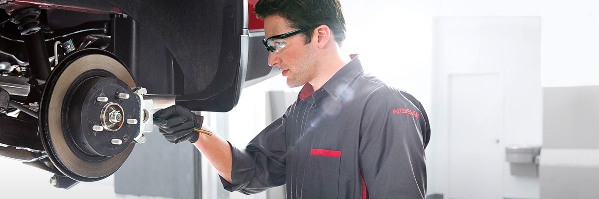 service technician looking at car brakes