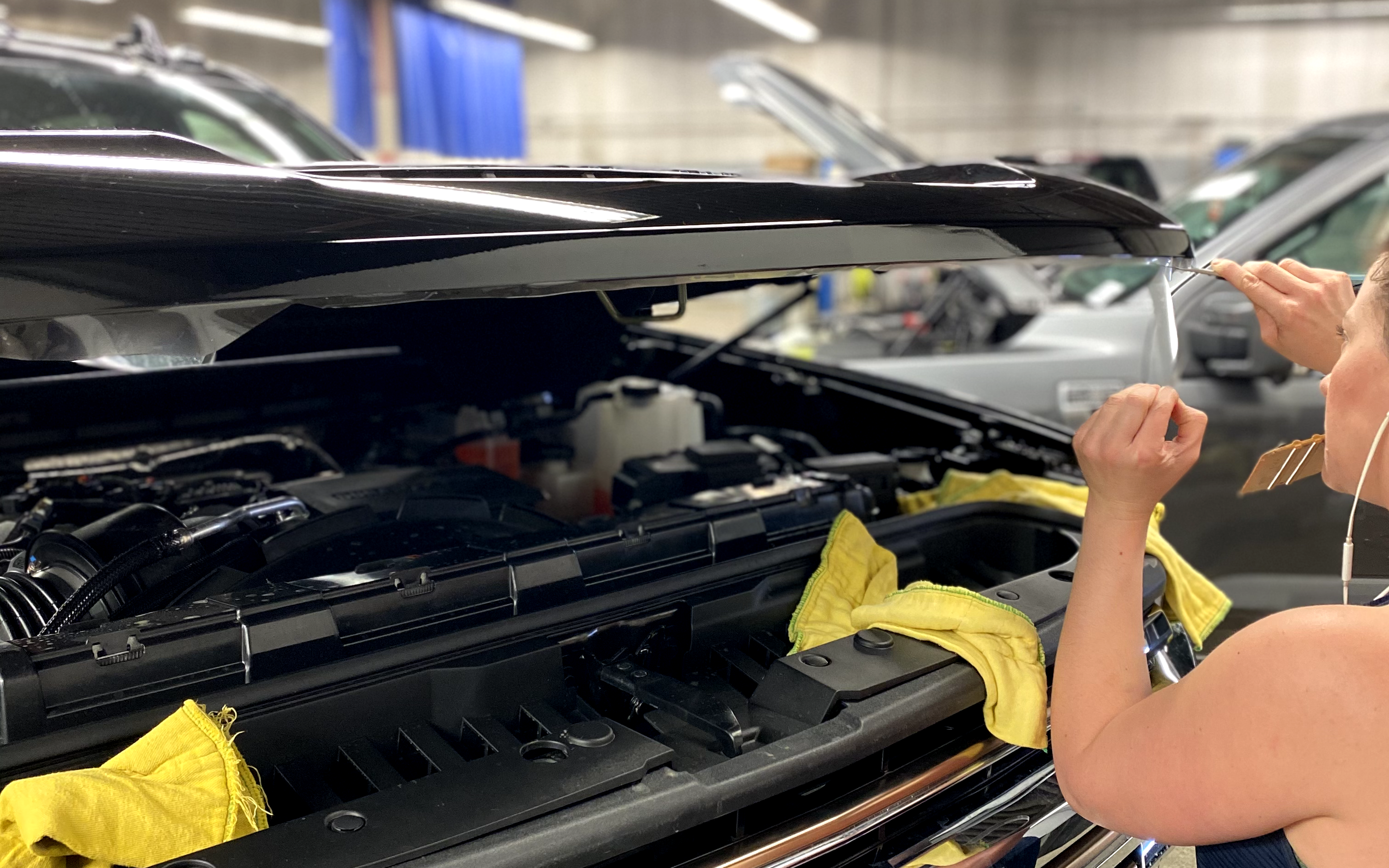 A woman applies film coating to a pickup truck