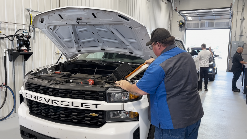 A man changes the air filter on a pickup truck