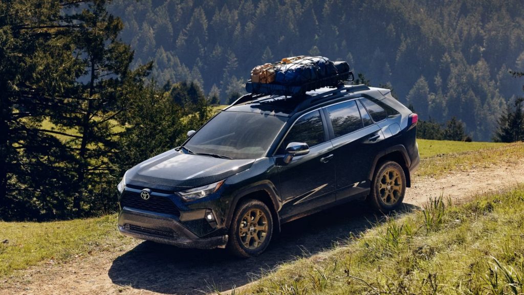 The new 2025 Toyota RAV4 is shown driving on a dirt path with a cargo holder on top. Shop for your new 2025 RAV4 at Johnson City Toyota.